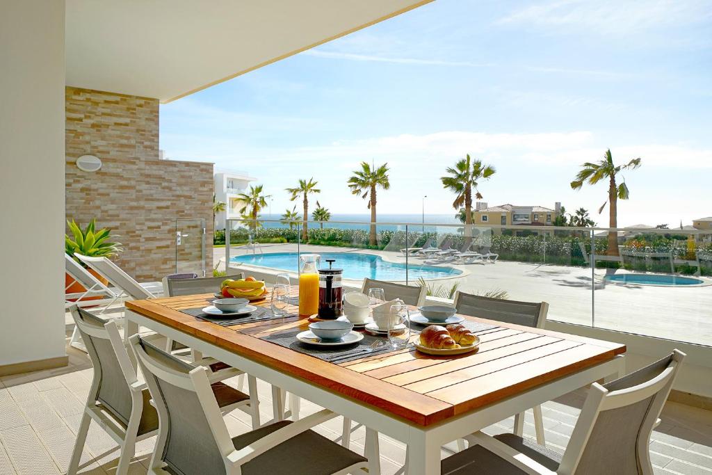 - une salle à manger avec une table, des chaises et une piscine dans l'établissement Brand New Luxury 3 Bedroom Apartment, Porto de Mos, à Porto de Mós
