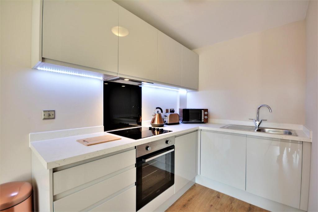 a kitchen with white cabinets and a sink at Quayside Central in Liverpool