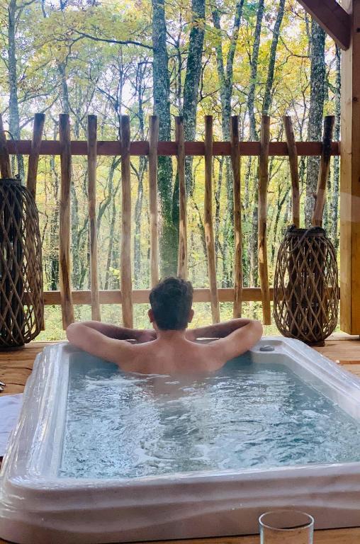 a man in a jacuzzi in a hot tub at Cabane Perchée Spa Dordogne La Ferme de Sirguet in Monsac