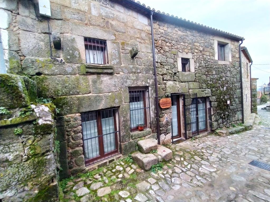 ein altes Steingebäude mit Fenstern auf einer Straße in der Unterkunft La Lagareta de Olivia in Trevejo