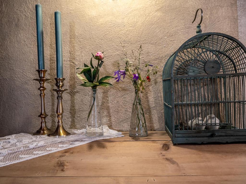 dos jarrones con flores y una jaula de pájaro sobre una mesa en Landhaus Strickenmacher en Sillian