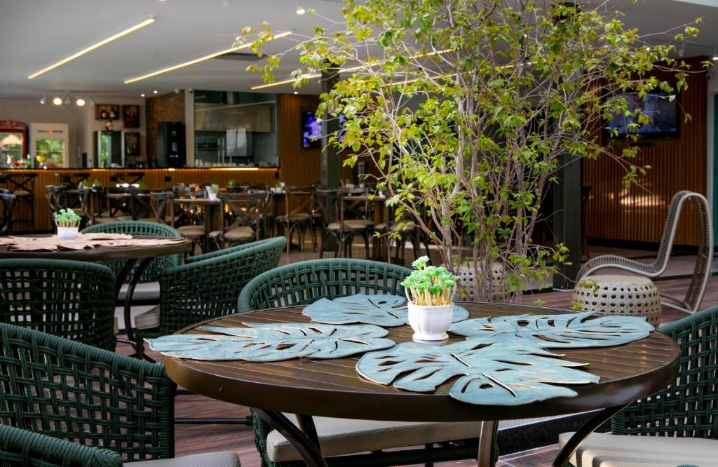 a table in a restaurant with chairs and tables with plants at Castelo Inn Hotel in Goiânia