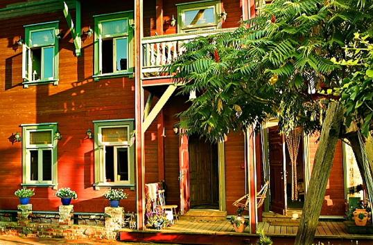 ein rotes Haus mit einer Veranda und einer Treppe in der Unterkunft Fontaine Valhalla Hotel in Liepāja