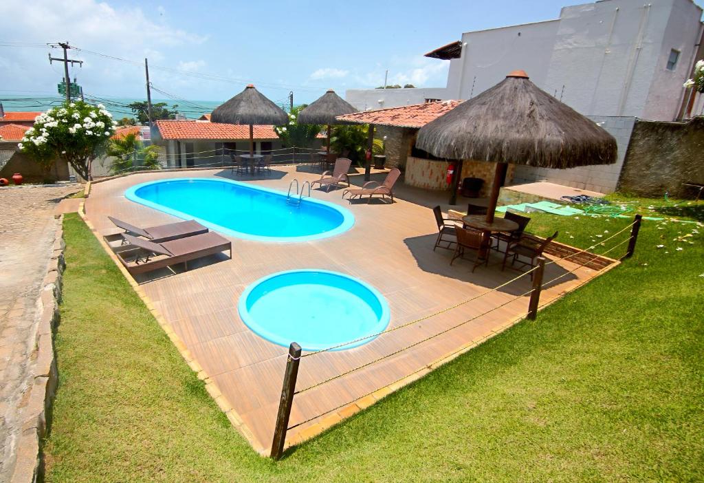 a swimming pool with two chairs and a table at Apart Hotel Litoral Sul in Natal