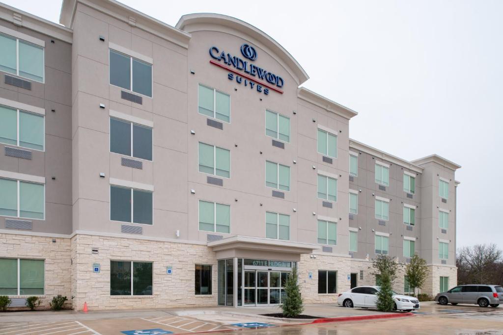 an exterior view of a building with cars parked in a parking lot at Candlewood Suites - Austin Airport, an IHG Hotel in Austin