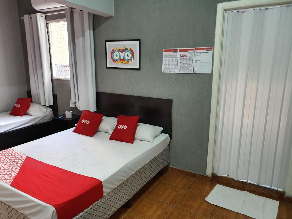 a bedroom with a bed with red pillows on it at Hotel Mogi in Mogi das Cruzes