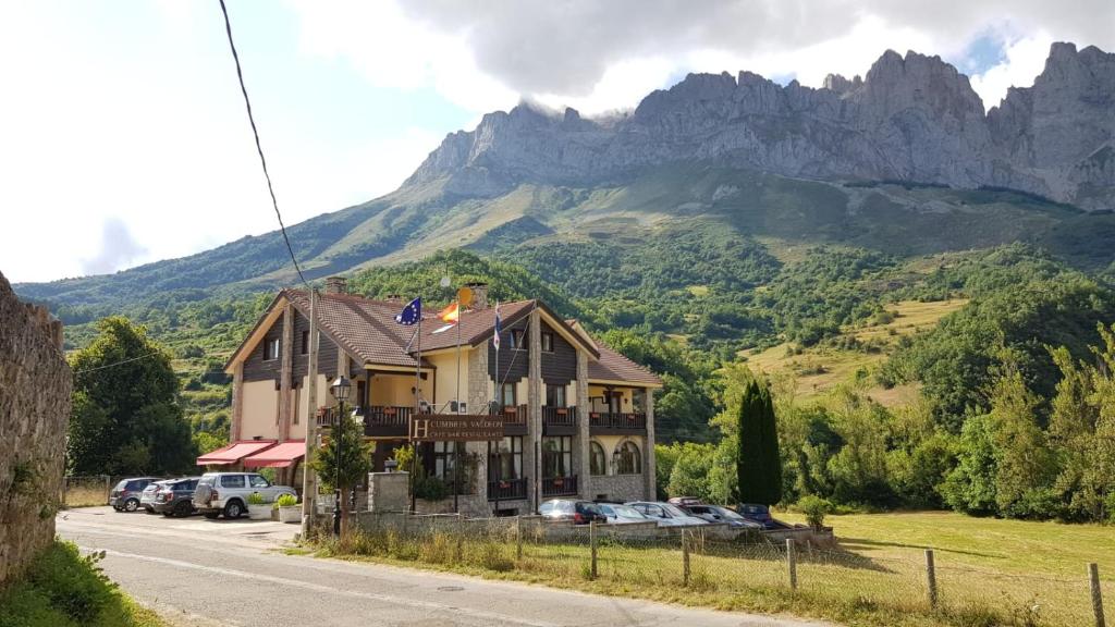 uma casa ao lado de uma estrada com uma montanha em Hotel Cumbres de Valdeón em Posada de Valdeón