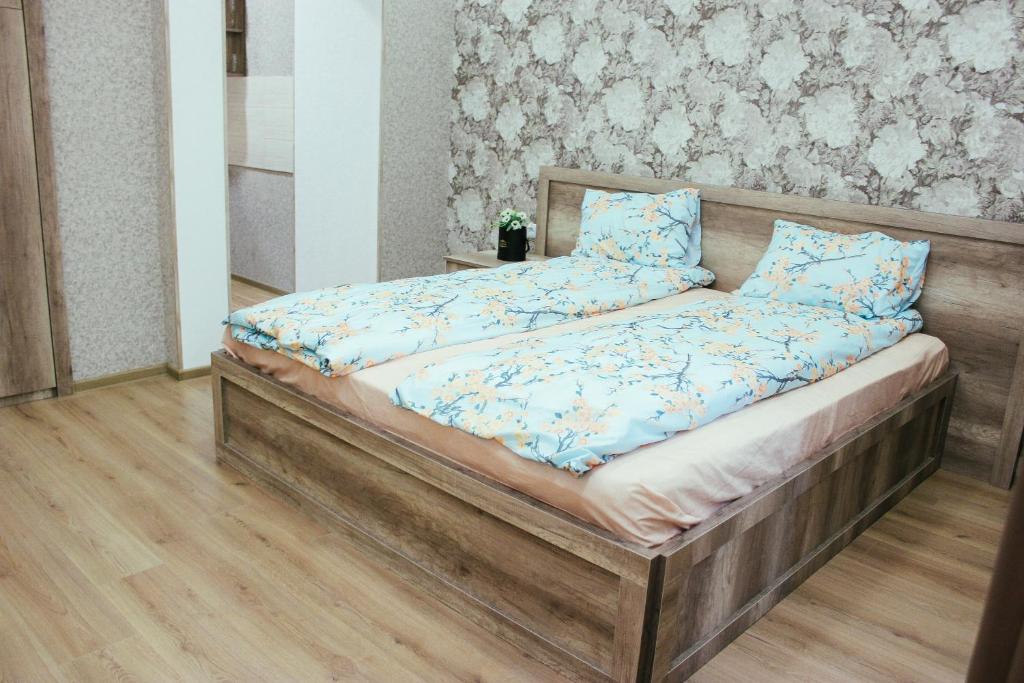 1 dormitorio con cama de madera y almohadas azules en Apartment Izabella, en Tiflis