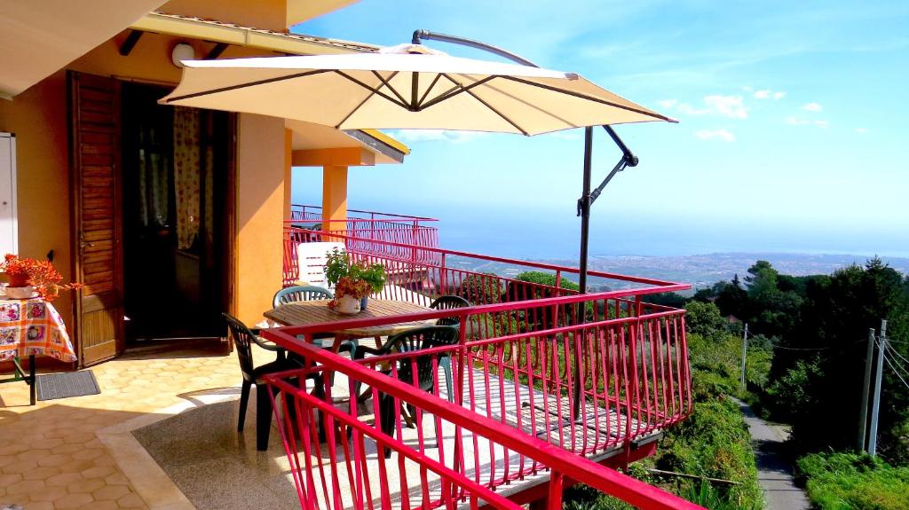 a balcony with a table and an umbrella at Casa La Vigna in Puntalazzo