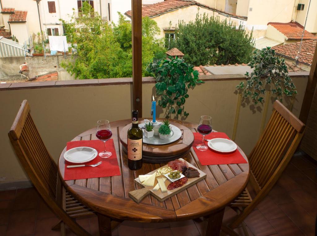 ein Holztisch mit einer Flasche Wein und Essen darauf in der Unterkunft Romantico Balcone in Centro in Florenz