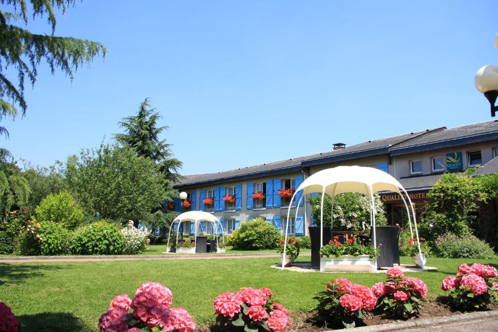 un jardín con 2 cenadores y flores en La Berteliere, The Originals Relais (Qualys-Hotel) en Saint-Martin-du-Vivier