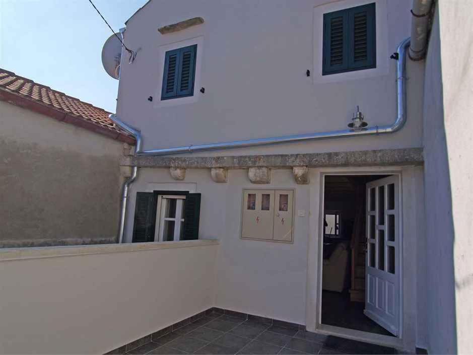 a white house with a door and a building at Apartments in Veli Losinj 14994 in Veli Lošinj