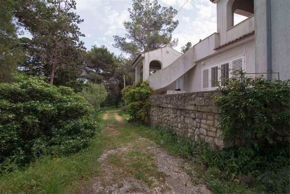 a stone retaining wall next to a house at Apartment in Veli Losinj 34684 in Veli Lošinj