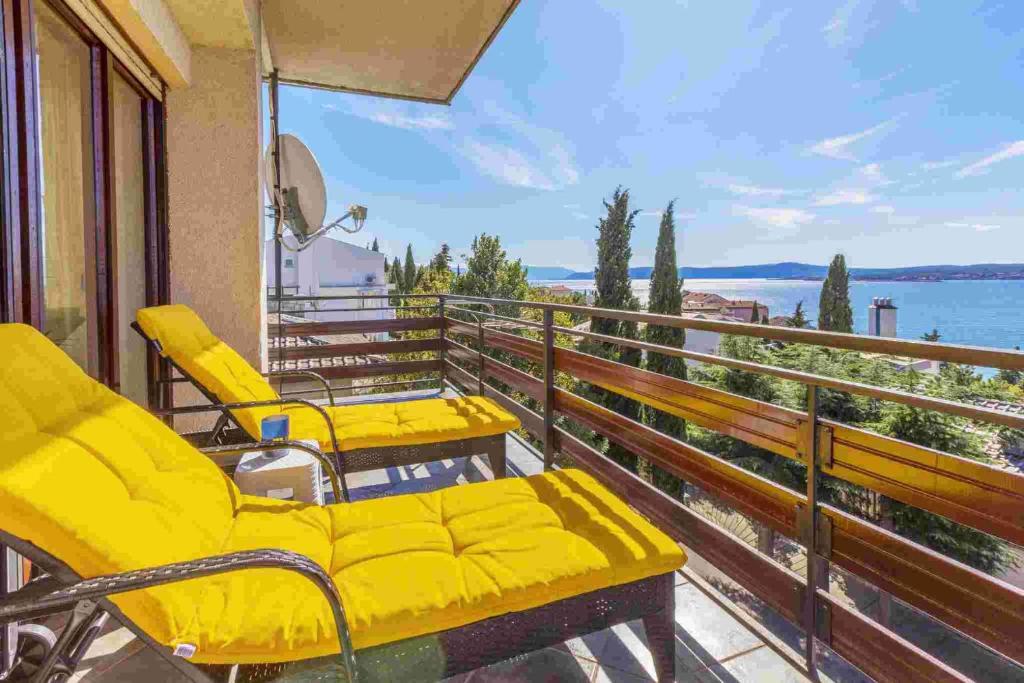 uma varanda com cadeiras amarelas e vista para a água em Apartment in Crikvenica 14231 em Crikvenica