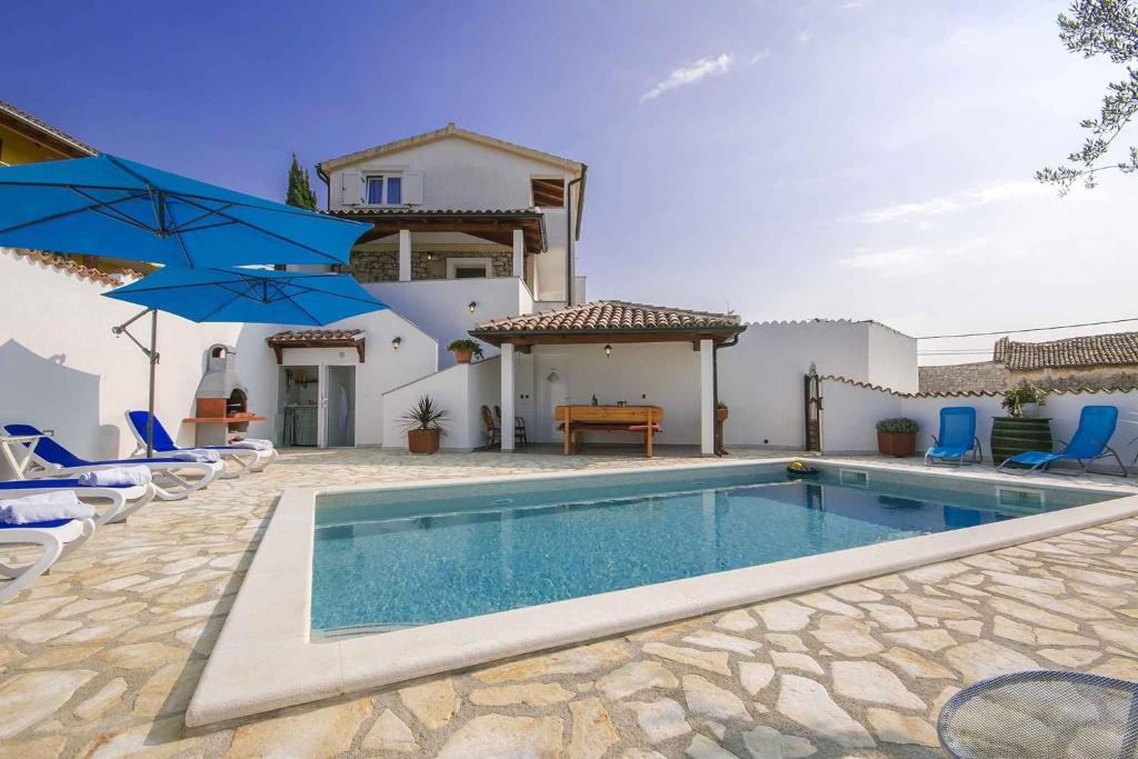 basen przed domem z niebieskimi parasolami w obiekcie Holiday home in Porec 35381 w mieście Dračevac