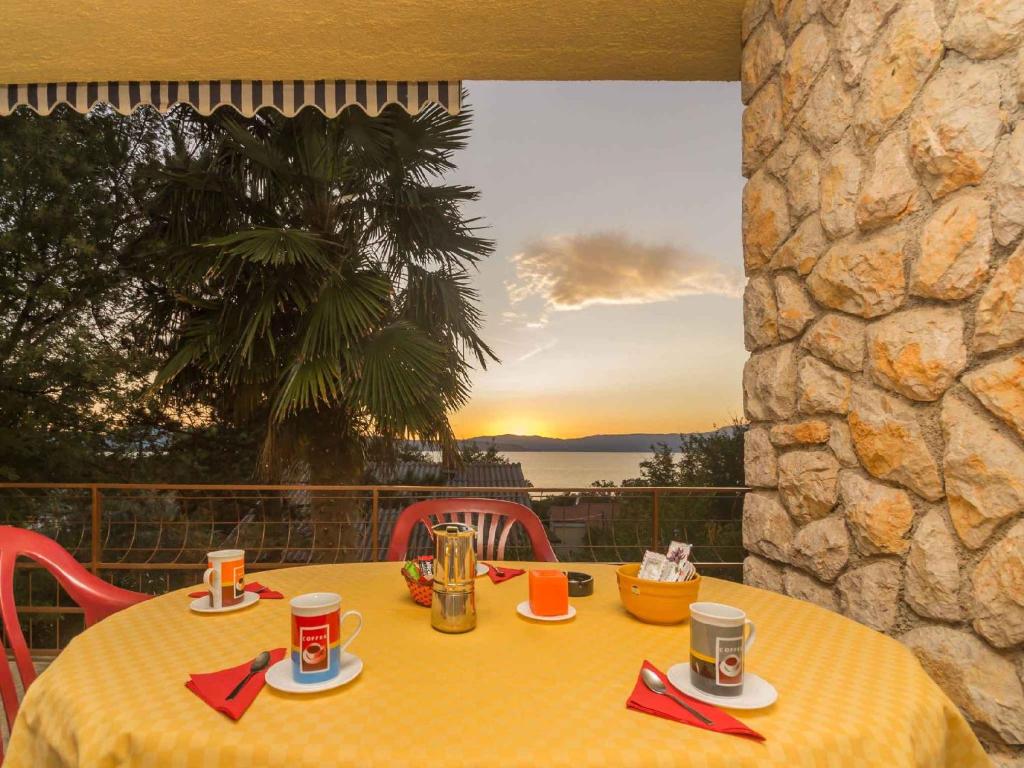 a table with a yellow table cloth on a balcony with the sunset at Apartment in Njivice/Insel Krk 33553 in Njivice