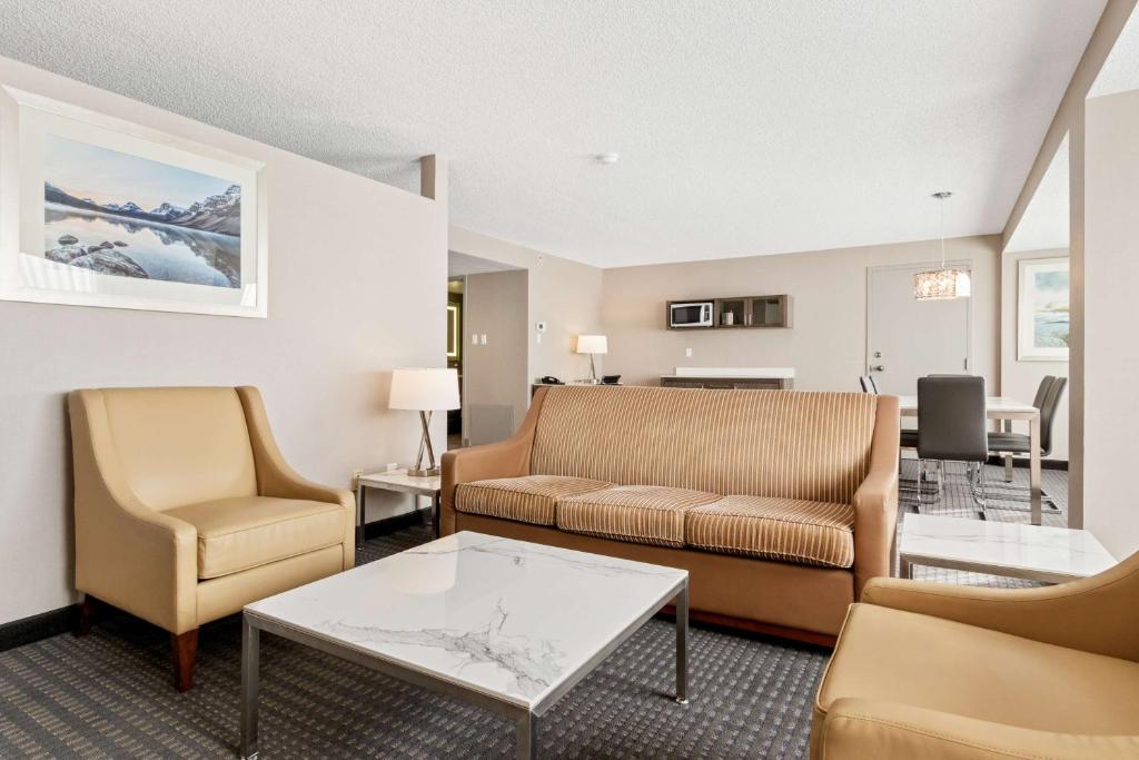 カルガリーにあるBest Western Premier Calgary Plaza Hotel & Conference Centreのソファと椅子とテーブルのあるリビングルーム