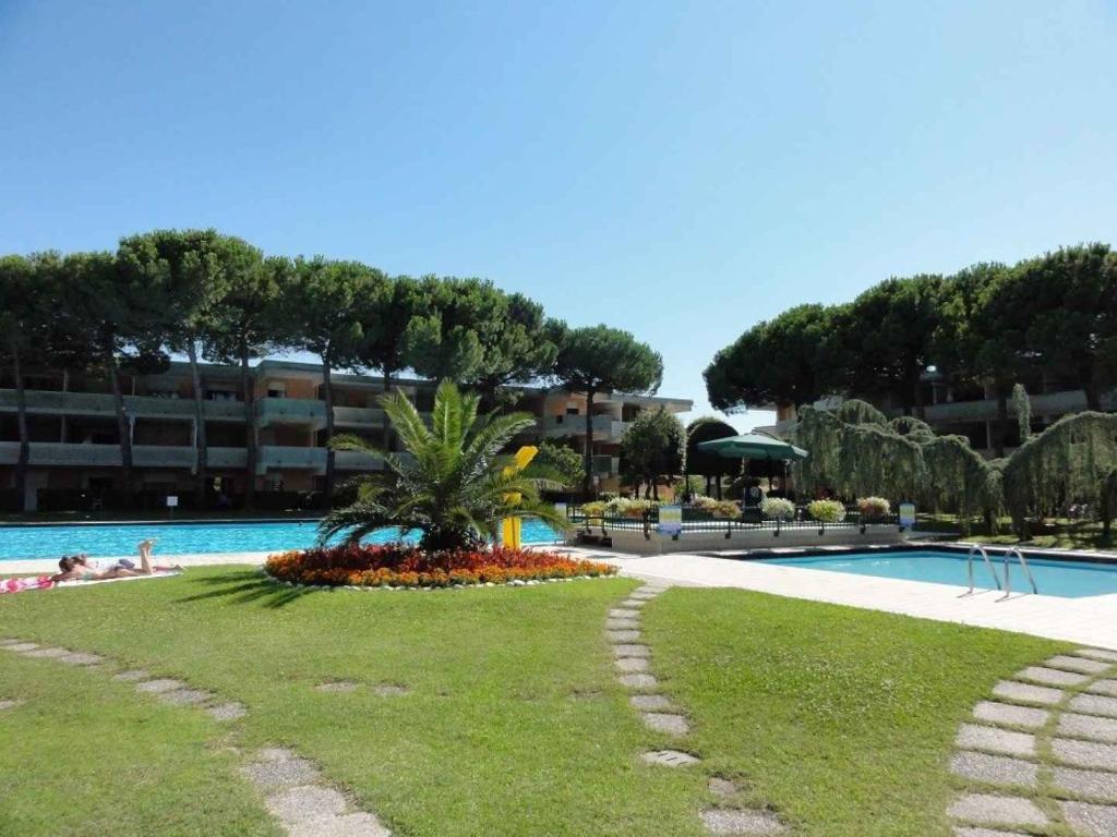 比比翁的住宿－Apartment in Bibione 24636，草上种着棕榈树,设有游泳池的度假村