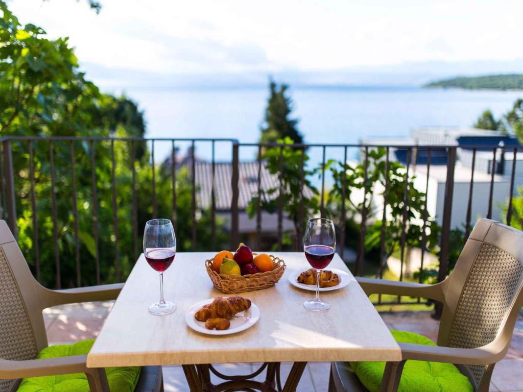 a table with two glasses of wine and a basket of fruit at Apartment in Njivice/Insel Krk 27658 in Njivice