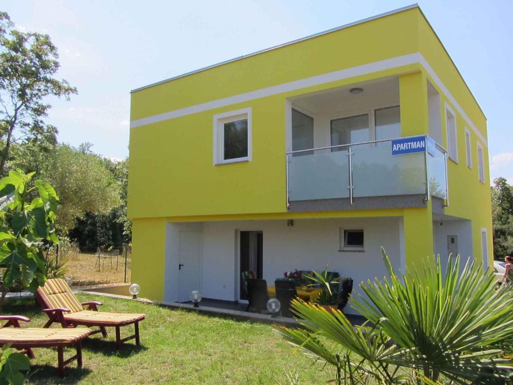 a yellow and green house with picnic tables in front of it at Two-Bedroom Apartment in Malinska/Insel Krk 13080 in Sveti Vid-Miholjice