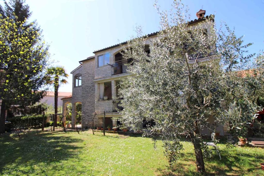 stary dom z drzewem przed nim w obiekcie Apartment in Porec/Istrien 10034 w Poreču