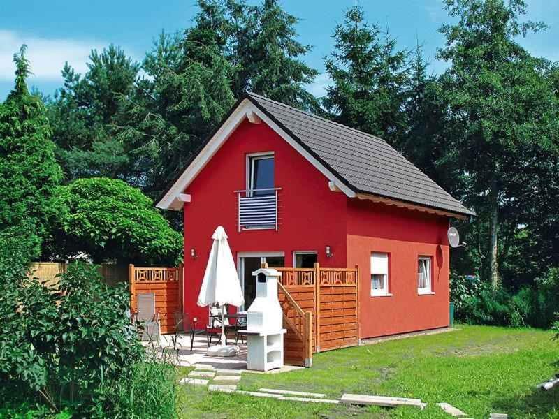 uma casa vermelha com um guarda-chuva e uma mesa em Holiday home in Zinnowitz (Seebad) 33031 em Zinnowitz