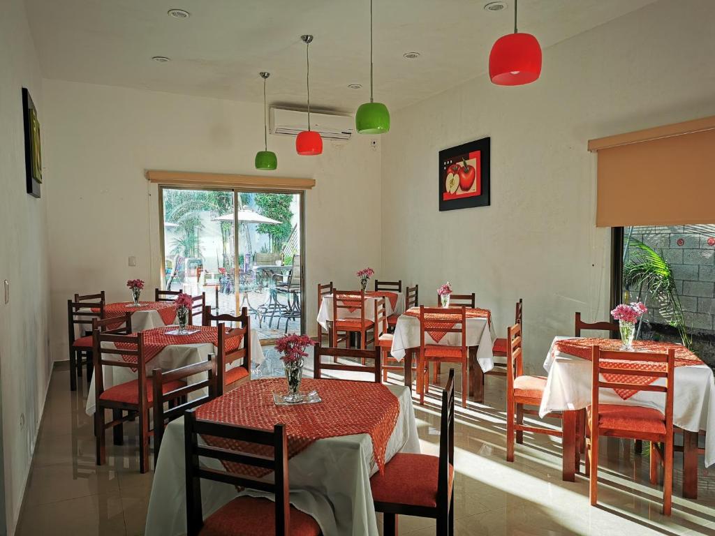 un comedor con mesas, sillas y sillas rojas en Hotel Real Mercedes en Mérida