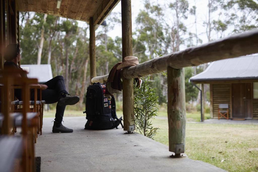 eine Person, die auf einer Veranda mit einer Gepäcktasche sitzt in der Unterkunft River Run Lodge in Strathblane
