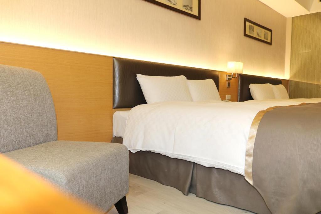a hotel room with two beds and a chair at Tsun Huang Hotel in Chiayi City