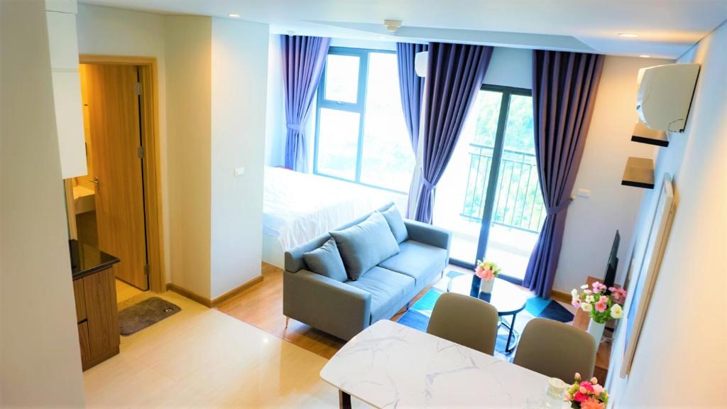 sala de estar con sofá azul y cama en Ecobay Halong -Mountain view and near Marina beach en Ha Long