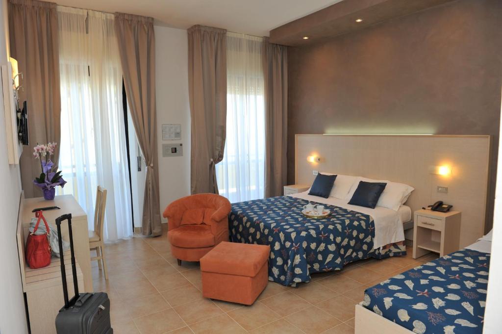 a hotel room with a bed and a chair at Hotel Mimosa in Riccione