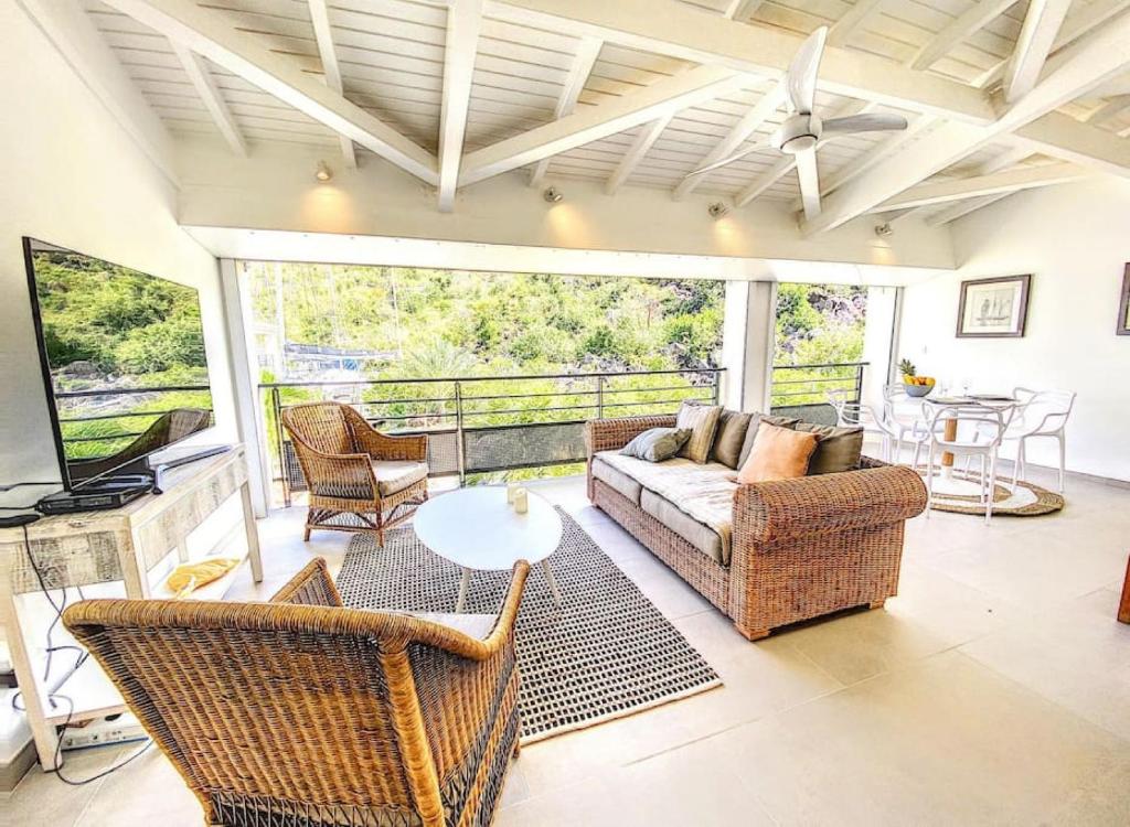 uma sala de estar com um sofá, uma mesa e cadeiras em Acacia Marina, luxurious Duplex, walkable beach em Anse Marcel 