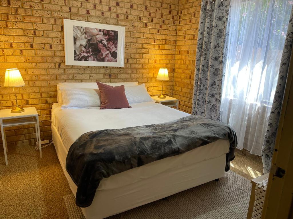 a bedroom with a bed and a brick wall at Esperance Holiday Apartment in Esperance