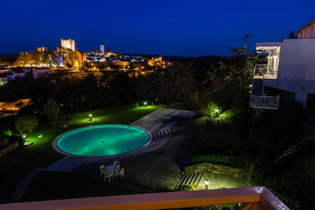 a swimming pool at night with a city in the background at Pousada de Bragança - Sao Bartolomeu in Bragança