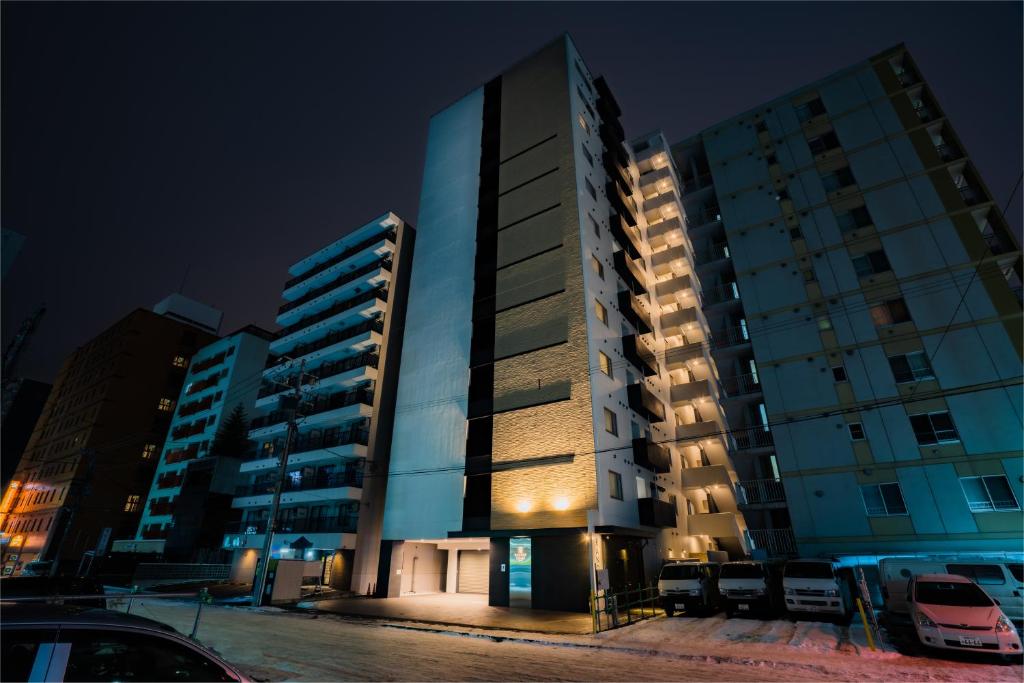 a tall building in a parking lot at night at Randor Hotel Sapporo Suites in Sapporo