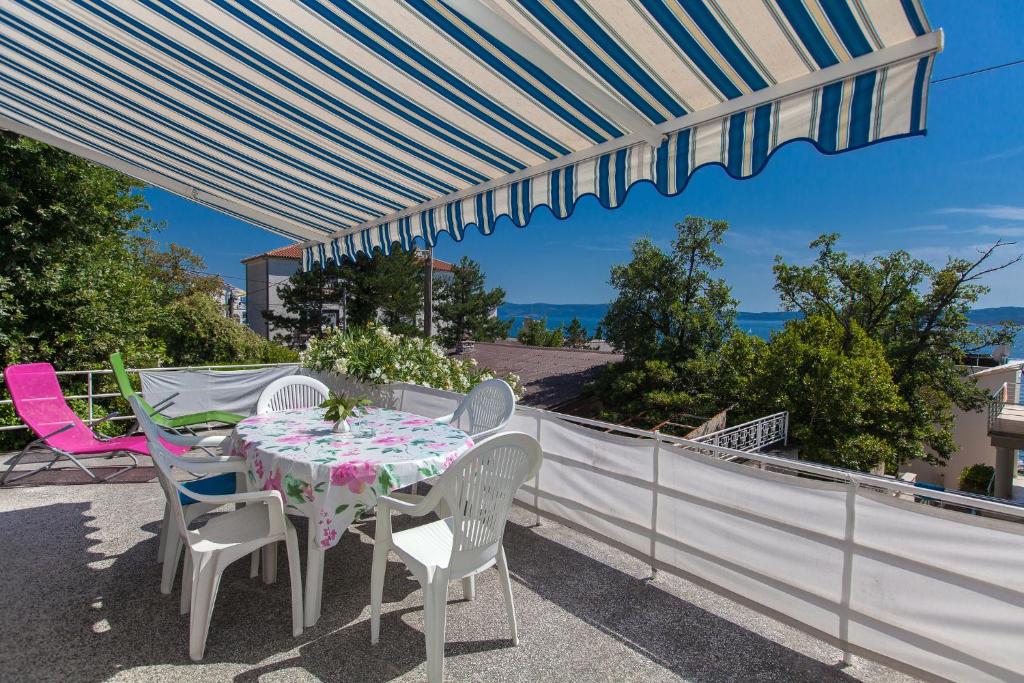 einen Tisch und Stühle auf einem Balkon mit Sonnenschirm in der Unterkunft BOZENA in Crikvenica