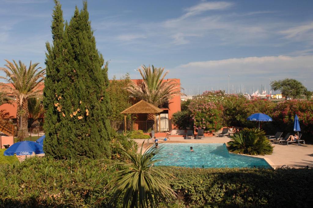 una piscina en un complejo con palmeras en Résidence Odalys Du Golfe, en Cap d'Agde