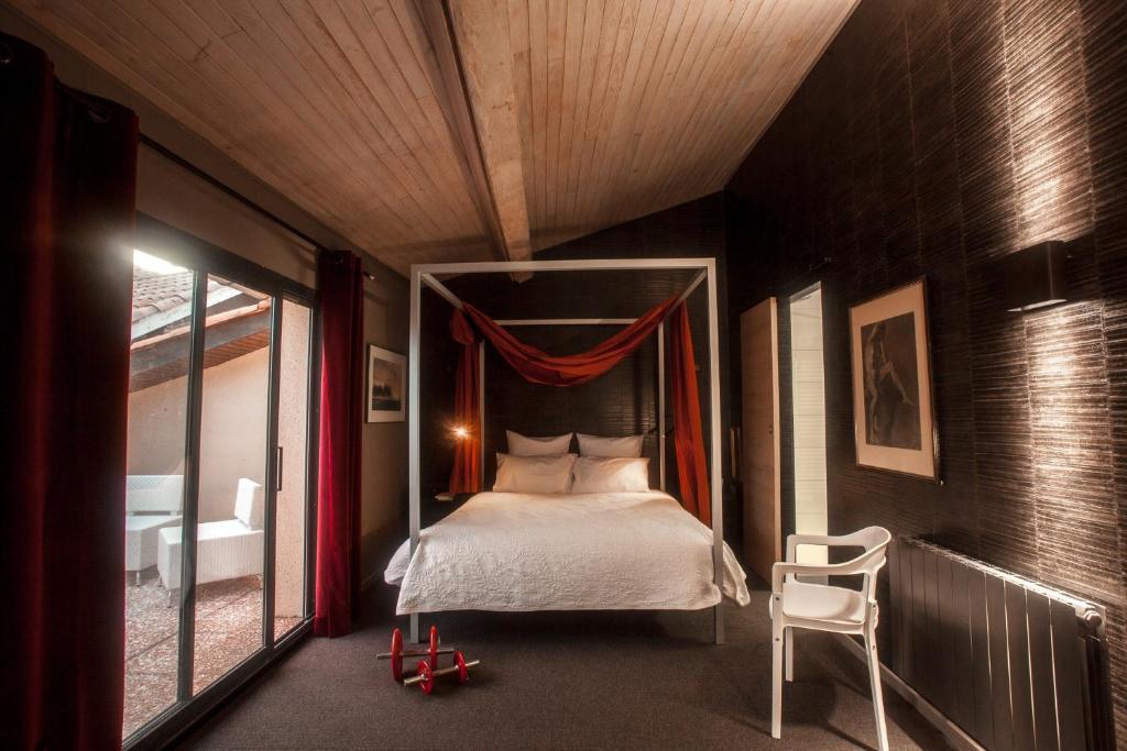 1 dormitorio con cama con dosel y silla en La Closerie aux Violettes - Maison d'hôtes, en Toulouse