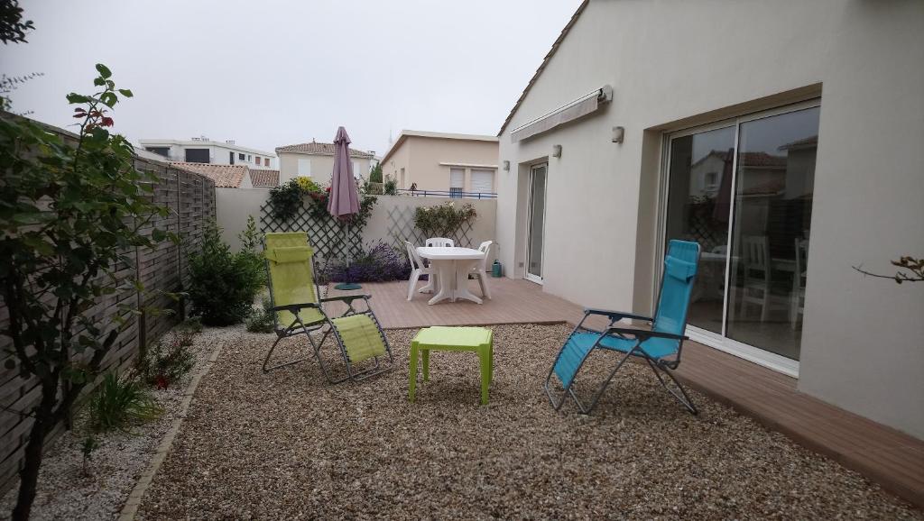 a group of chairs and a table in a backyard at SYLCHRISVACANCES in Vaux-sur-Mer