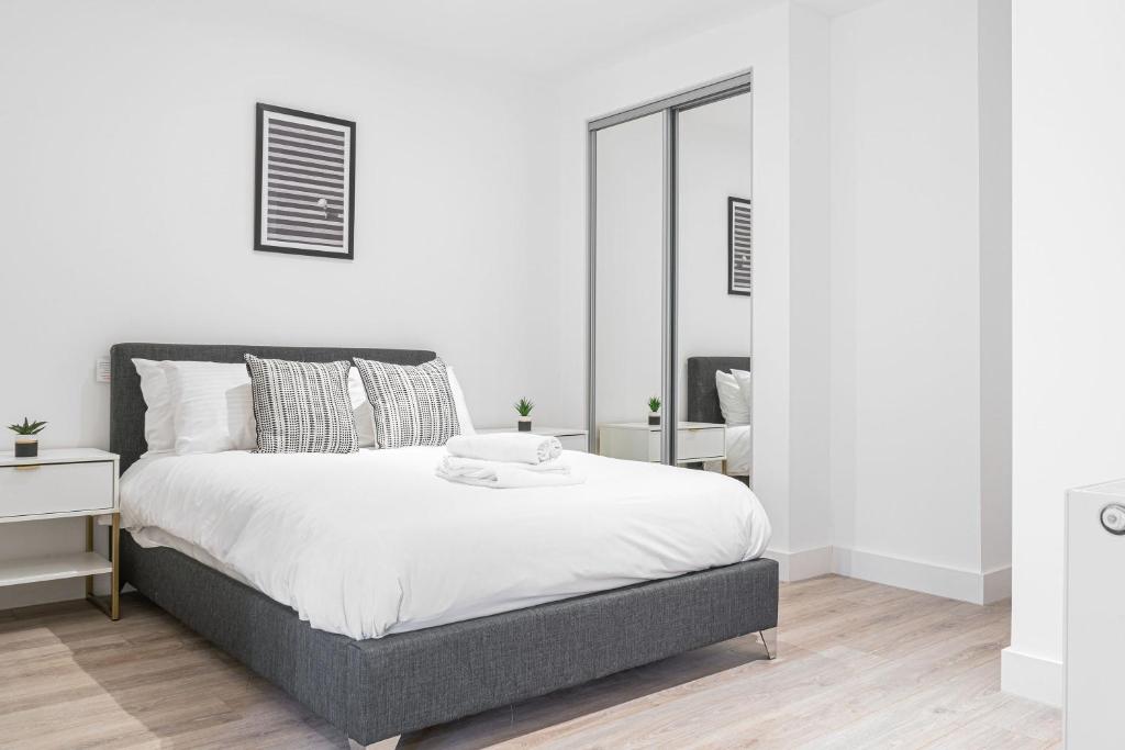 ein weißes Schlafzimmer mit einem Bett und einem Spiegel in der Unterkunft Seven Living Residences Solihull - Close to NEC & BHX - Free Parking in Solihull