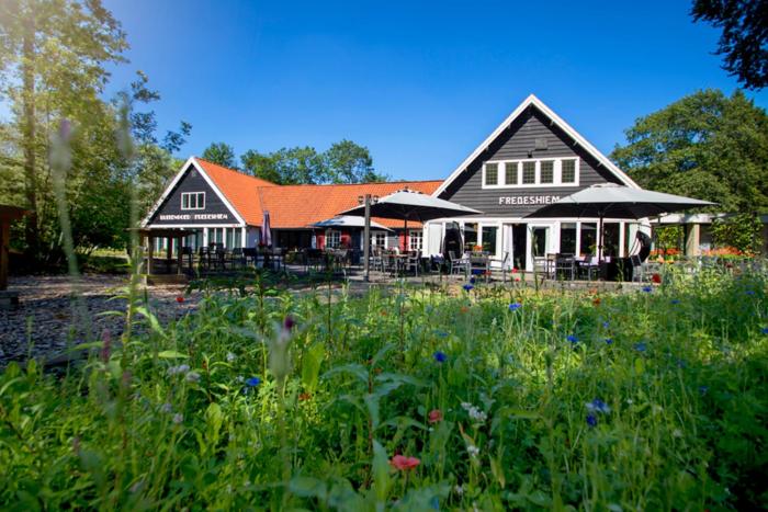 a building with a field of flowers in front of it at Buitengoed Fredeshiem in De Bult