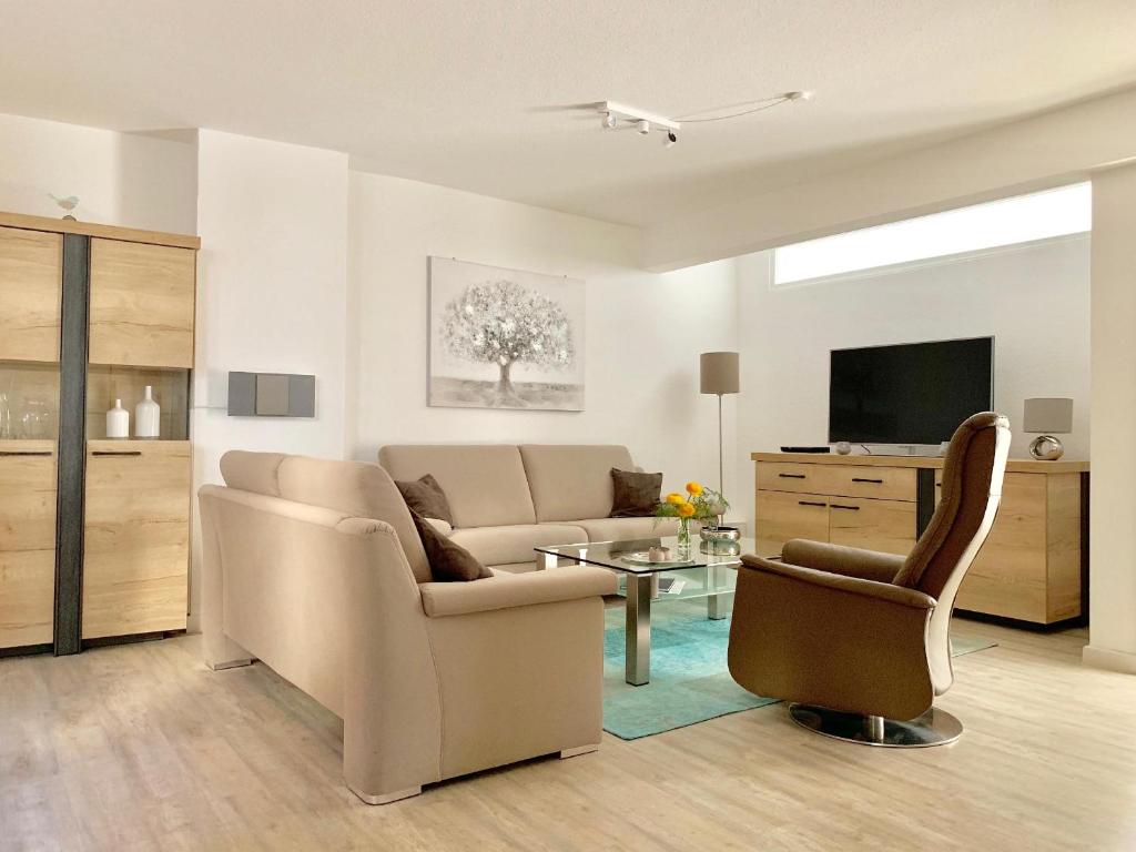 un soggiorno con divano, sedie e TV di fewo1846 - Atrium - luxuriöse Wohnung mit 3 Schlafzimmern und Balkon im Stadtzentrum a Flensburgo