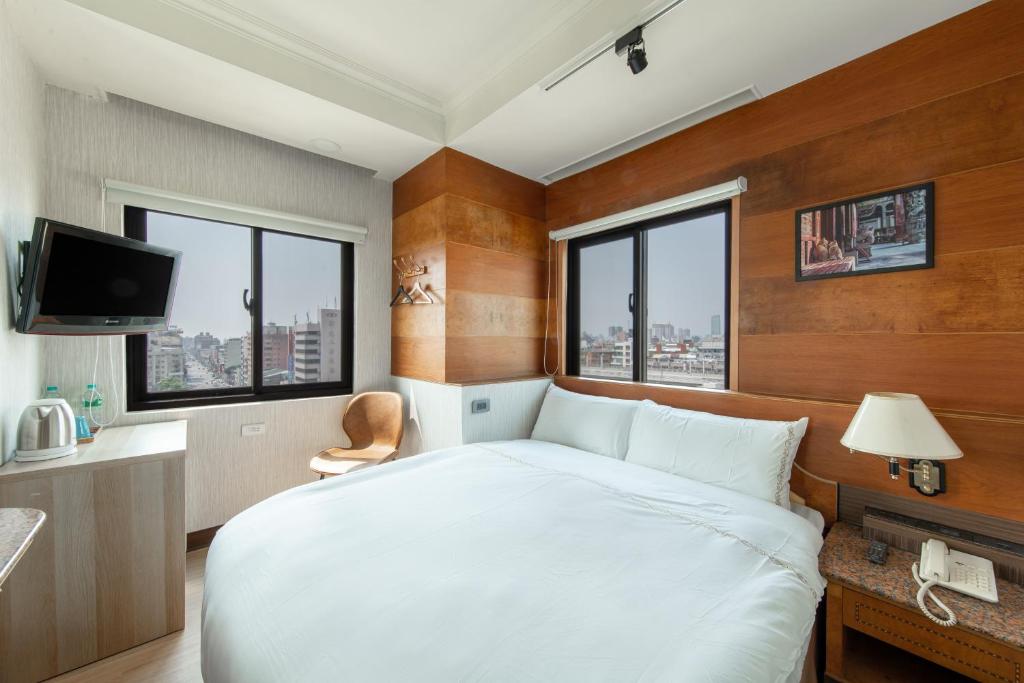 a bedroom with a large white bed and windows at 二川行旅 - HiRiver Hotel in Taichung