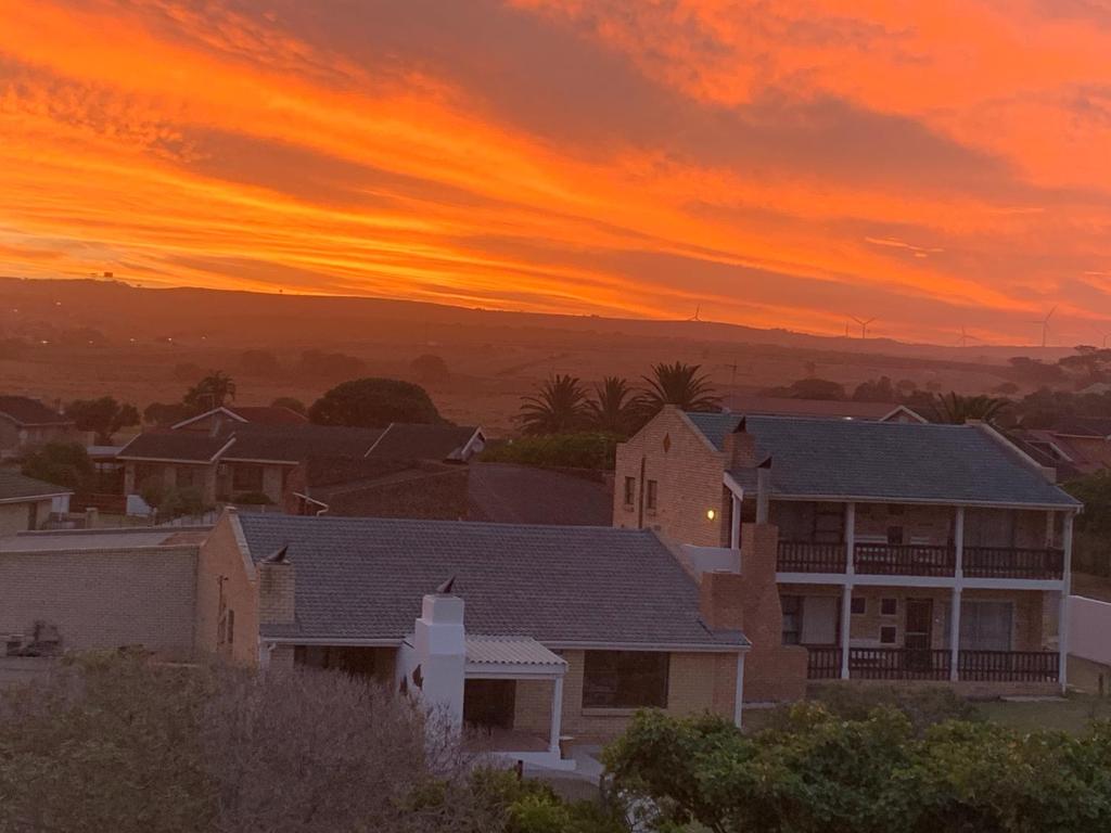 una casa en un suburbio con una puesta de sol en el fondo en 28 Kabeljauws, en Jeffreys Bay