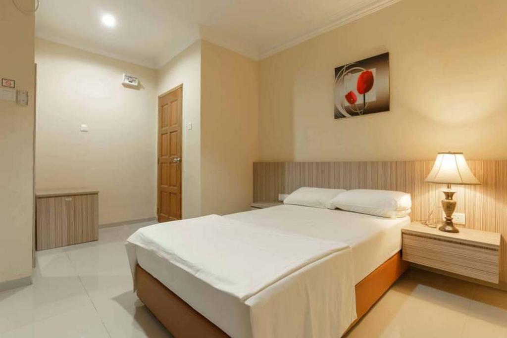 Un dormitorio con una gran cama blanca y una lámpara en Queen Inn Batam RedPartner, en Tanjungriau