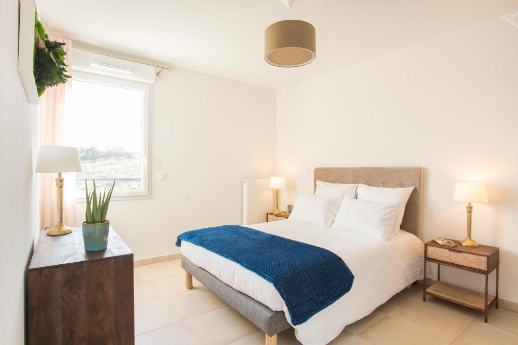 a white bedroom with a bed and a window at Zenao Appart'hôtels Villeneuve-lès-Avignon in Villeneuve-lès-Avignon