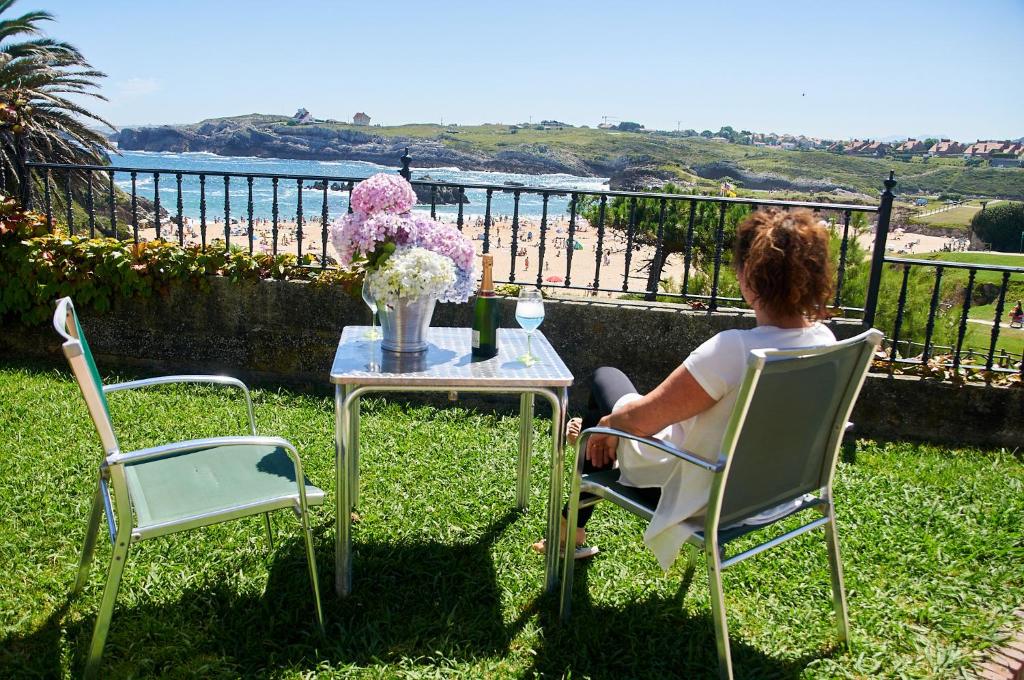a woman sitting at a table in front of a table with flowers at Posada La Morena in Soto de la Marina