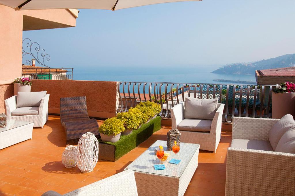 Un balcón con sillas y mesas y vistas al océano. en Bike&Boat Argentario Hotel en Porto Santo Stefano