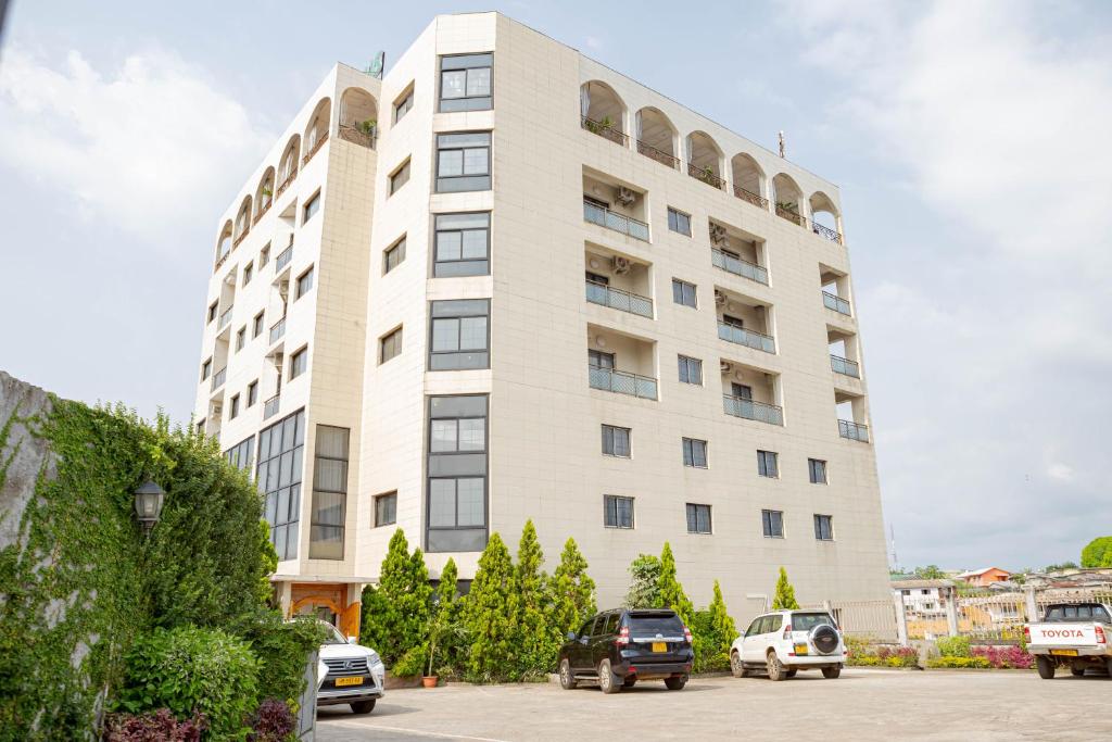 利伯维尔Hotel Hibiscus Louis的一座白色的大建筑,汽车停在停车场