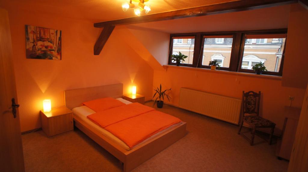 1 dormitorio con 1 cama de color naranja y 2 lámparas en Haus am Schloßberg, en Plauen